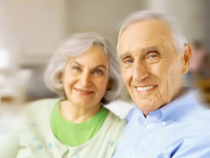 Casal de idosos sorrindo, rosto a rosto