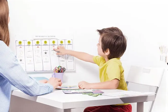 Criança apontando para quadro de atividades