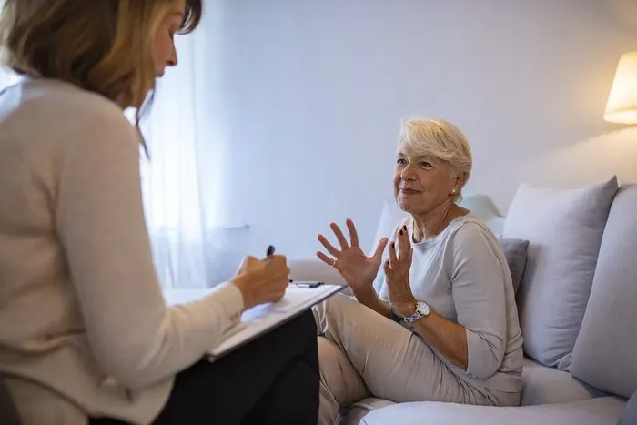 Terapeuta conversando com paciente idosa